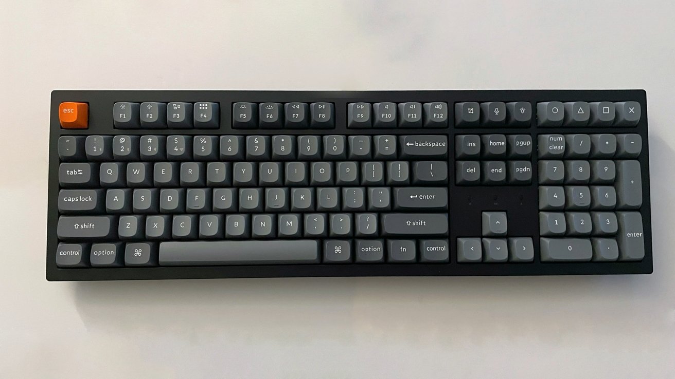 A black keyboard with dark grey keys, an orange Escape key, and a numeric keypad on the right.