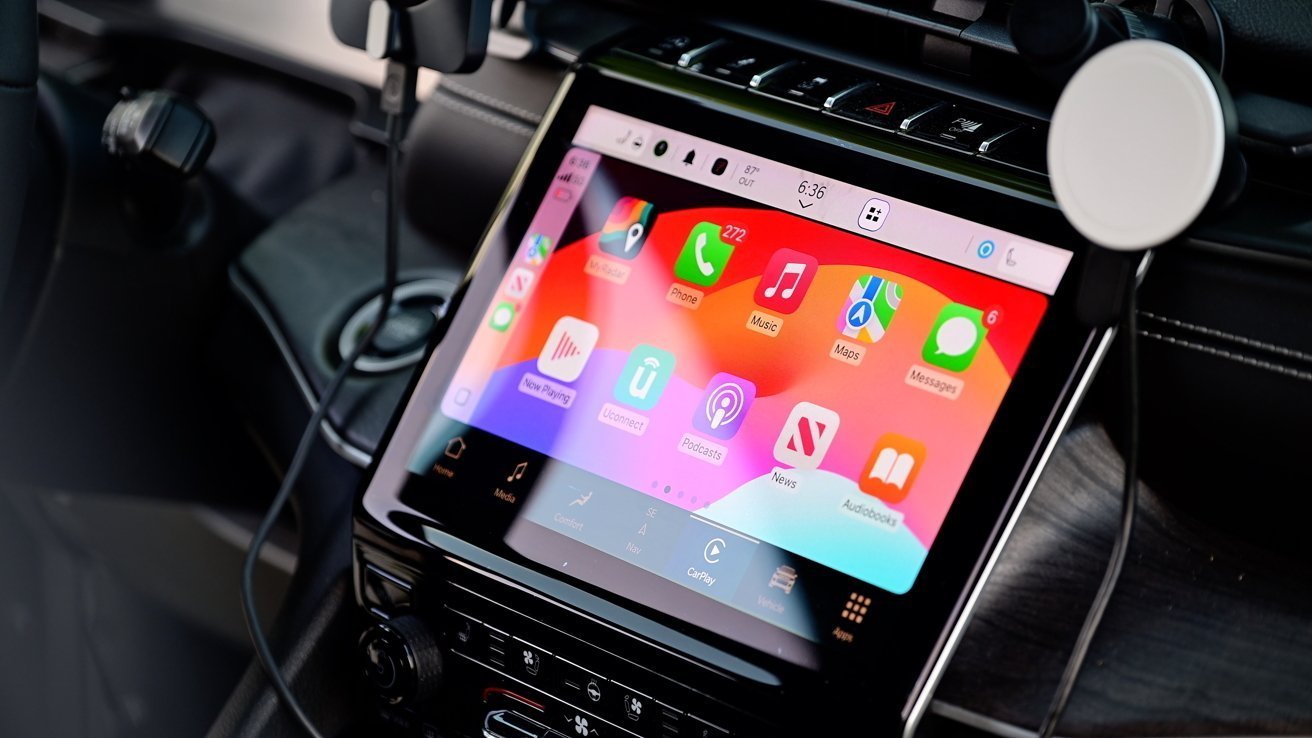 Car dashboard with a touchscreen displaying colorful app icons for phone, music, maps, podcasts, and messages.