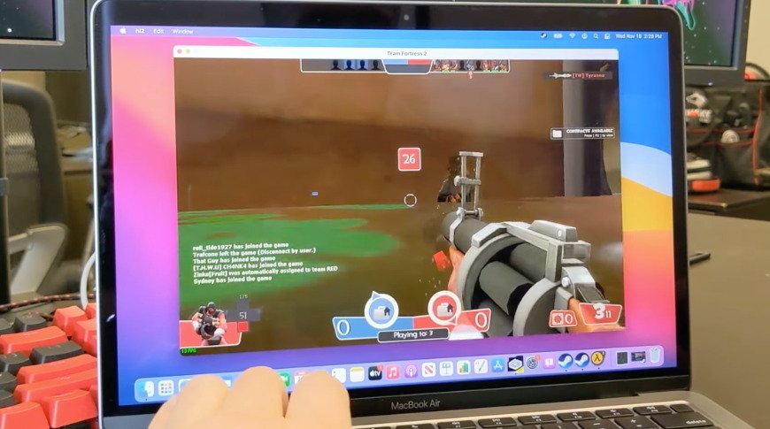 A person playing a first-person shooter game on a MacBook Air, with the in-game chat visible on the screen.