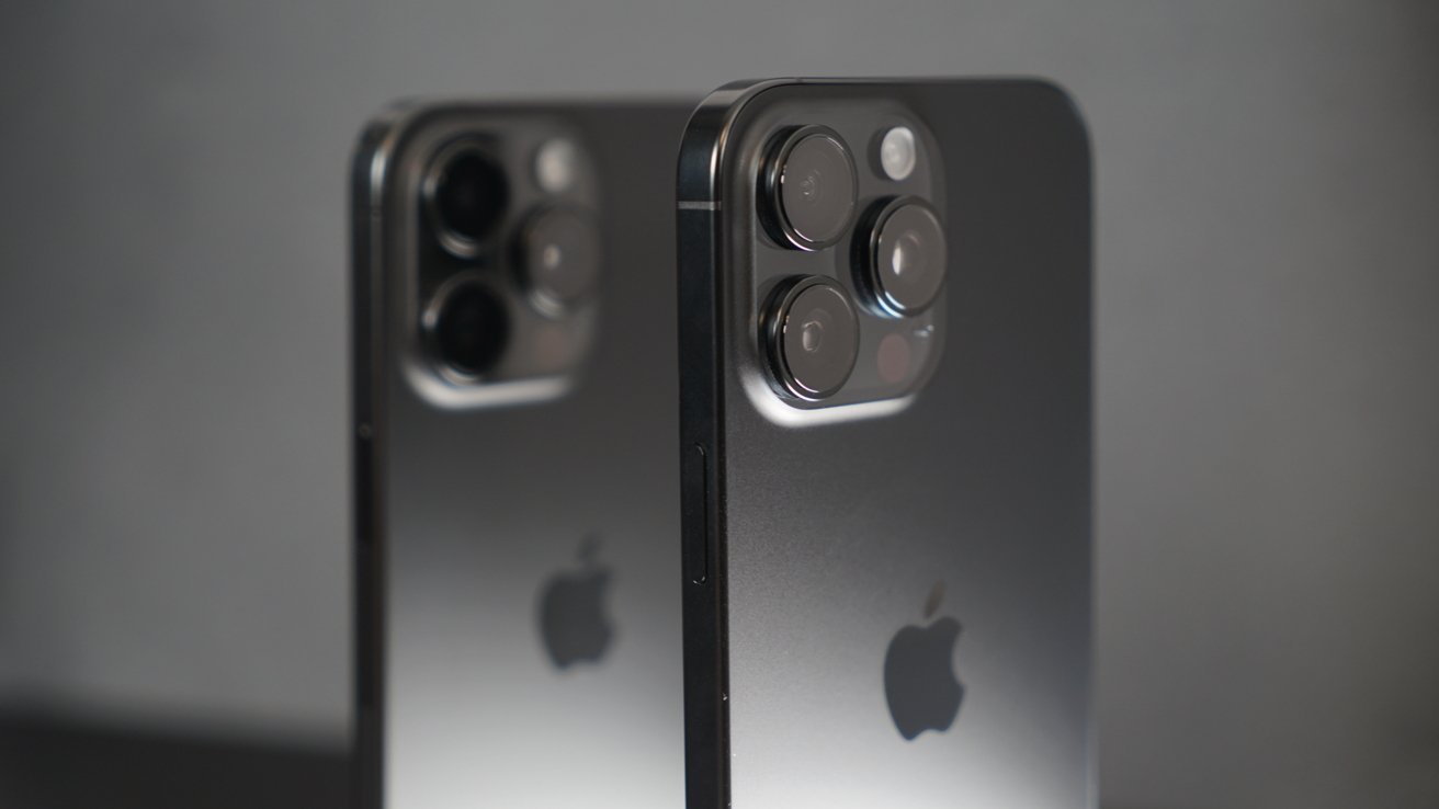 Two sleek smartphones in dark gray with multiple camera lenses, Apple logo visible on the back, positioned against a neutral background.