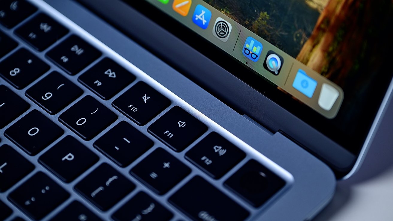 Close-up of a laptop keyboard and part of the screen showing application icons, including magnifier and text editor symbols.