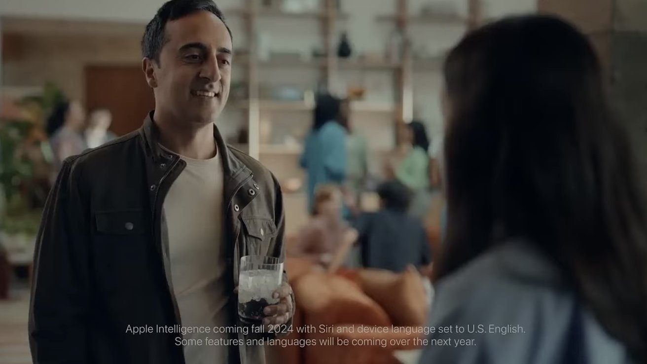 Man holding drink, smiling at a woman in a social gathering setting with blurred people and shelves in the background. Text about Apple Intelligence's 2024 release at bottom.