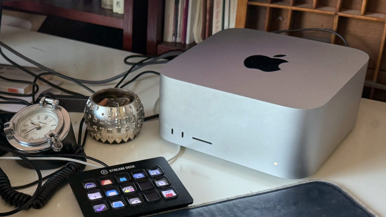 A computer, pocket watch, silver decorative cup, and stream deck with multiple buttons on a desk with cables.