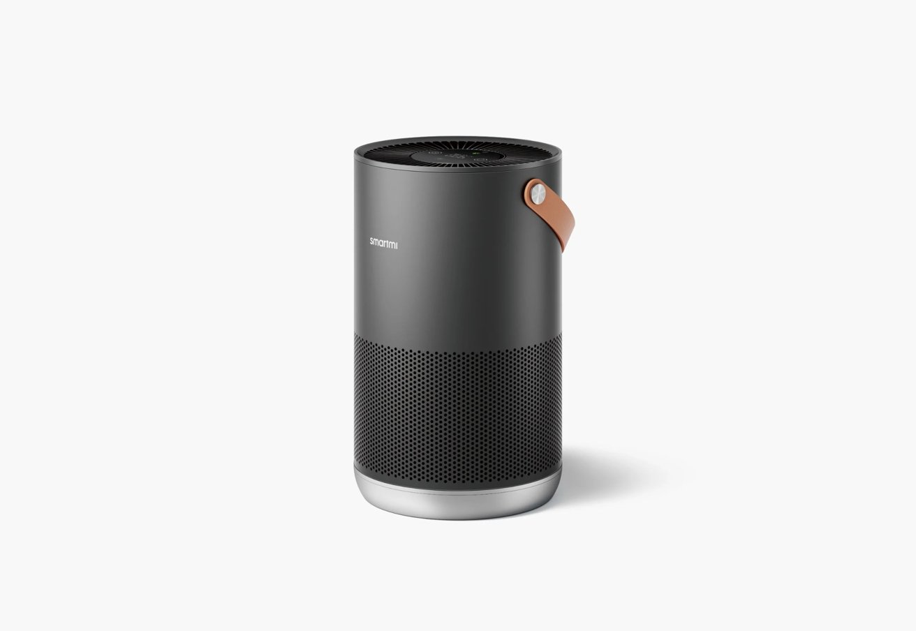 A sleek, cylindrical air purifier with a black finish, perforated lower section, and brown leather strap accent.
