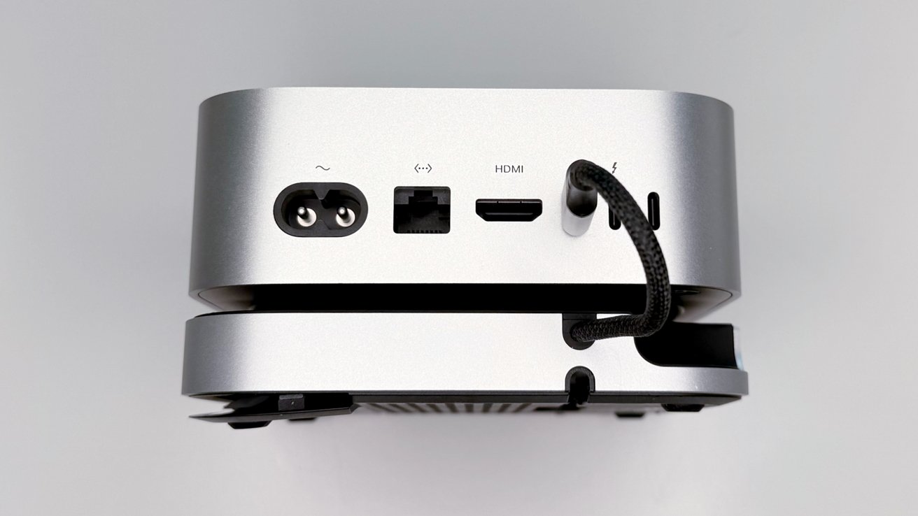 Silver electronic device with visible power, Ethernet, and HDMI ports on the back, showing a black cable plugged into a socket.