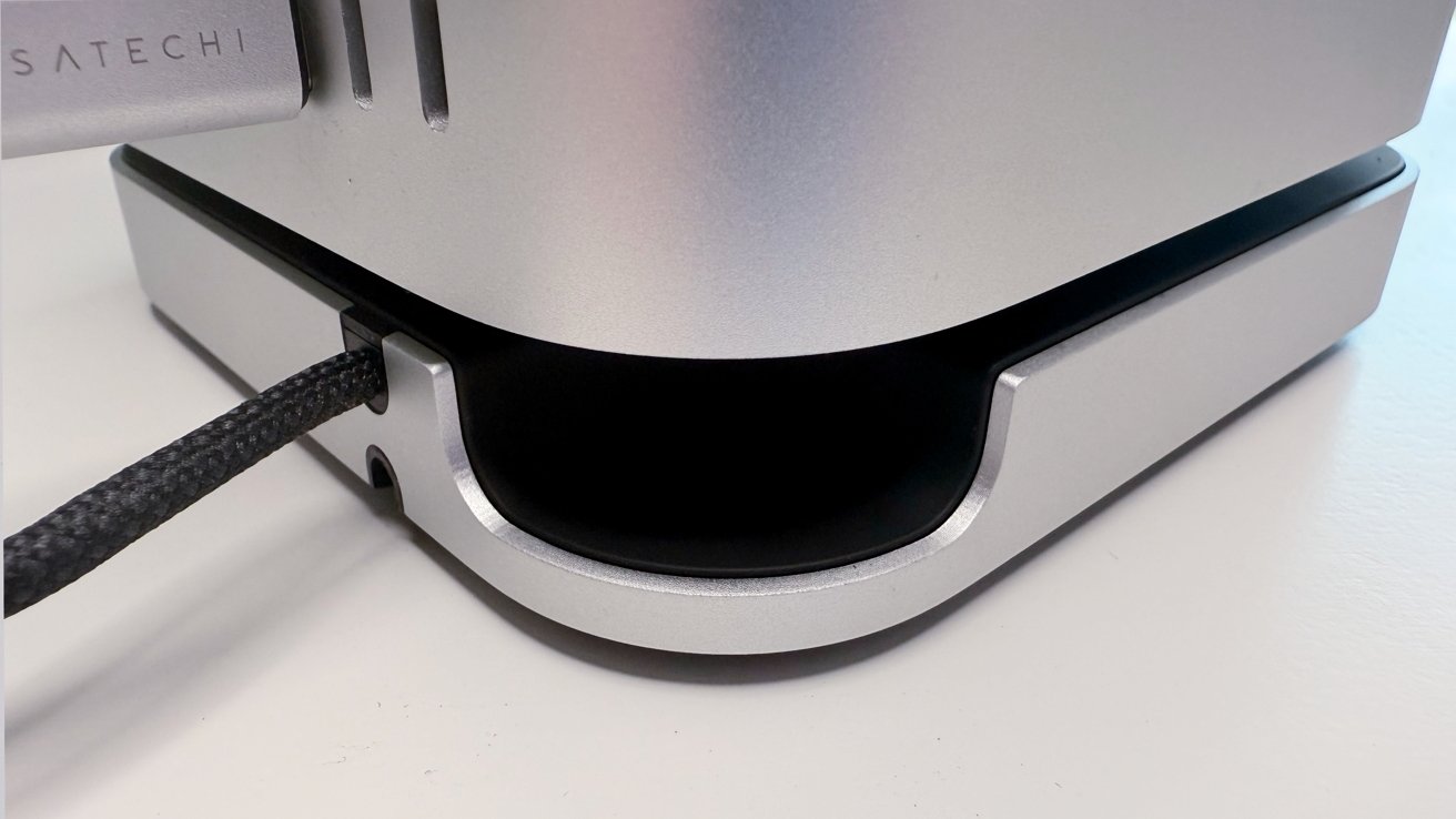 A sleek silver metal stand with a black braided cable inserted through a rounded slot, resting on a flat surface.