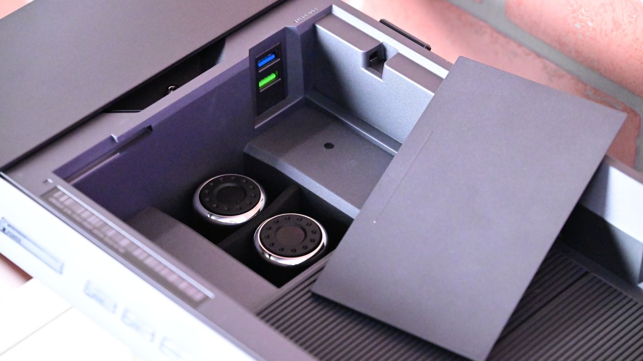 Open printer tray revealing two ink cartridges and USB ports, surrounded by black and gray components.