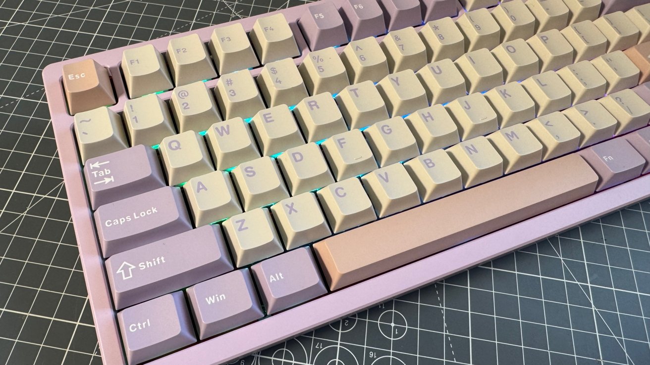 Purple and beige mechanical keyboard with blue LED lighting on a cutting mat with a grid pattern.