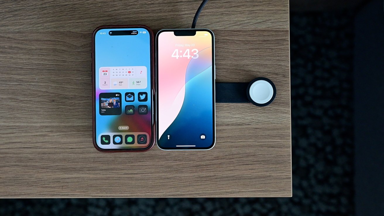 Two smartphones on a wooden table next to a round smartwatch charger. The left phone displays widgets, while the right shows a colorful lock screen with the time 4:43.