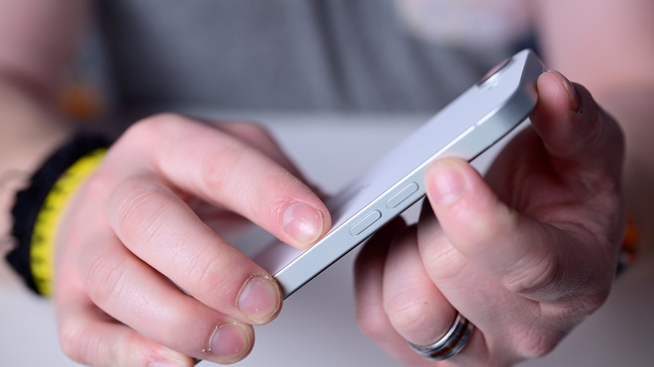 Someone pressing the side of a silver smartphone