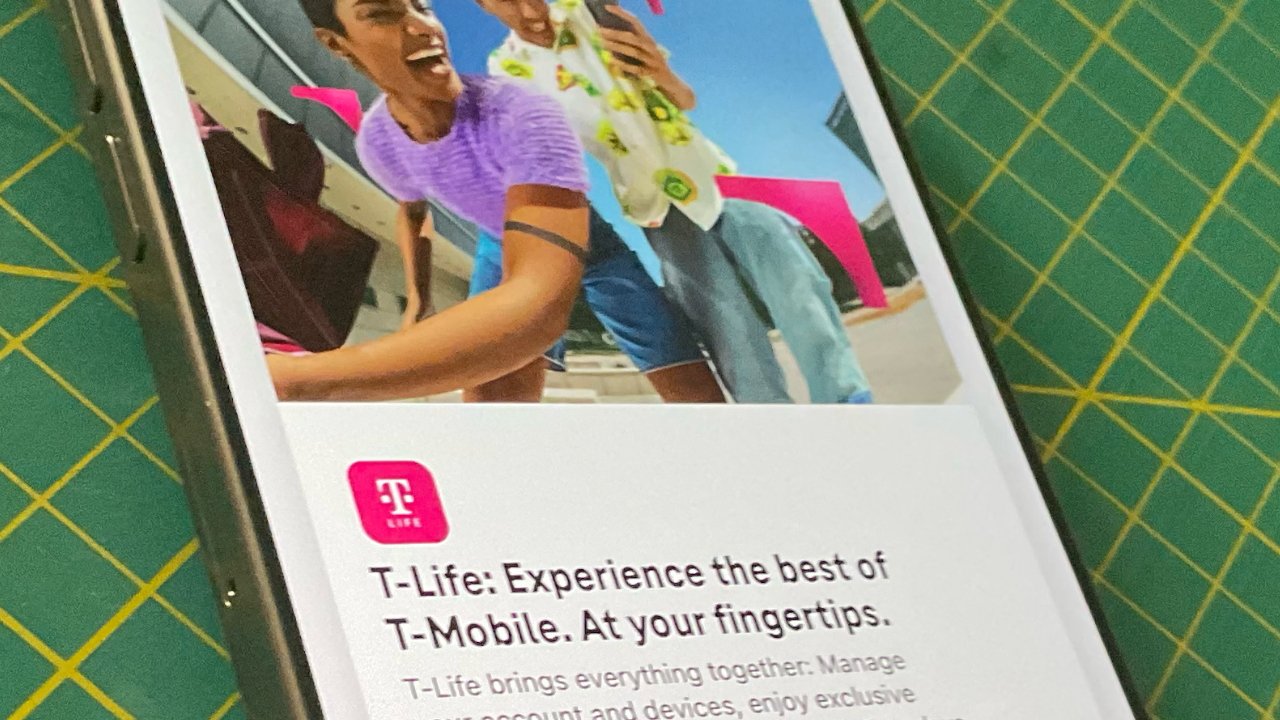 Two people smiling, taking a selfie outdoors with a smartphone. Text below reads 'T-Life: Experience the best of T-Mobile.' Placed on a grid-patterned surface.