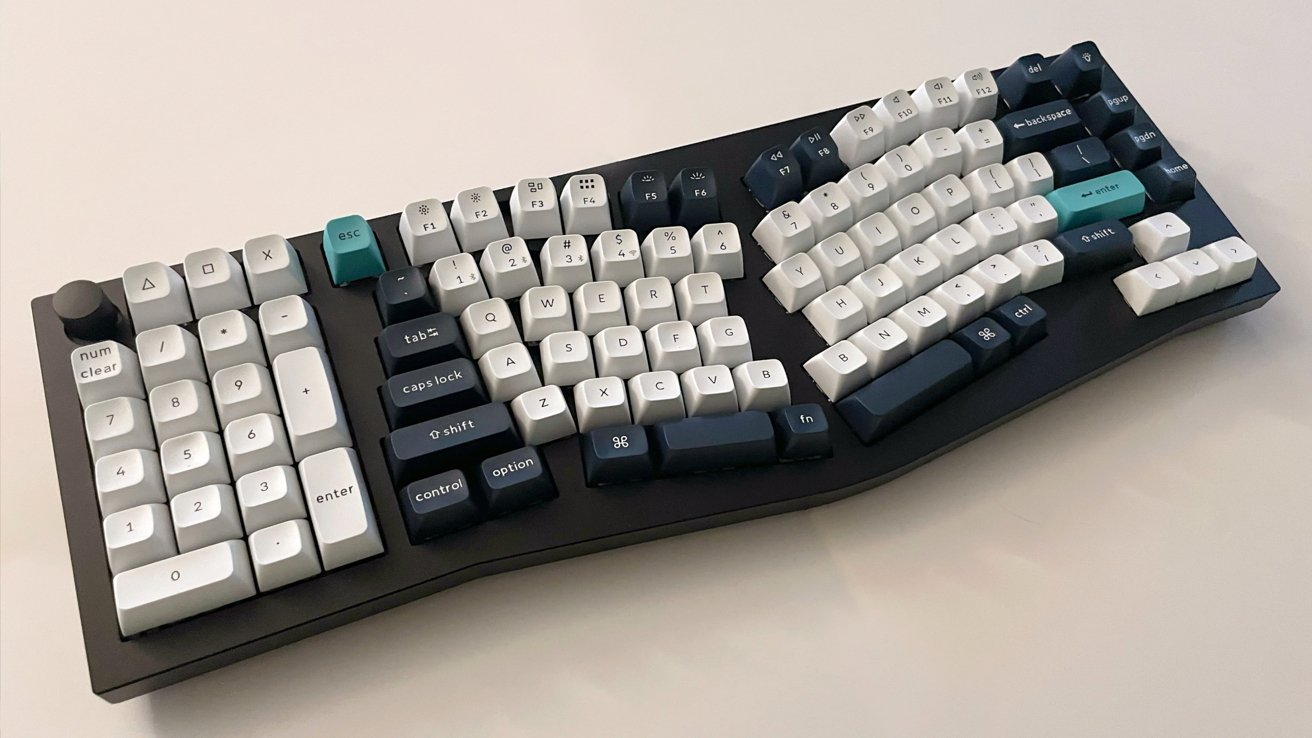 Ergonomic keyboard with white and dark blue keys on a curved layout, featuring teal escape and enter keys, a number pad, and a black base.