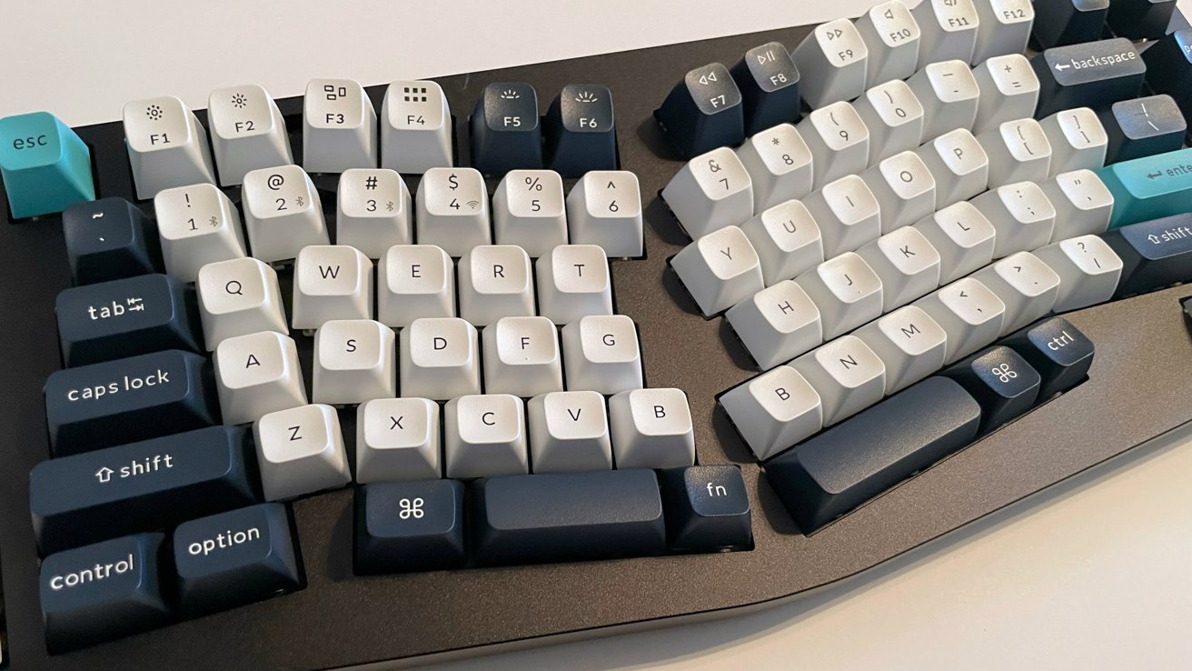 Mechanical keyboard with white and dark blue keys, featuring a teal escape key and a split ergonomic design.