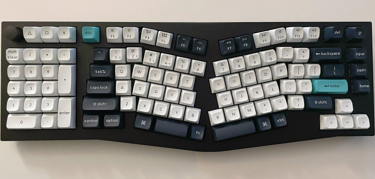 Ergonomic split keyboard with concave key layout, featuring a number pad on the left and teal accents on the escape and enter keys.
