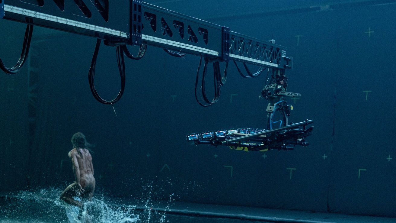 Large robotic camera crane over water as a person runs, causing splashes.