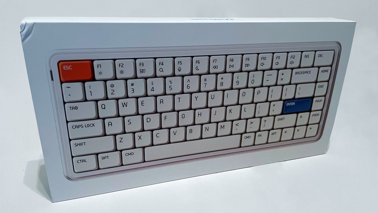 White keyboard with orange escape key and blue enter key, featuring standard keys and function buttons, displayed on a white box.