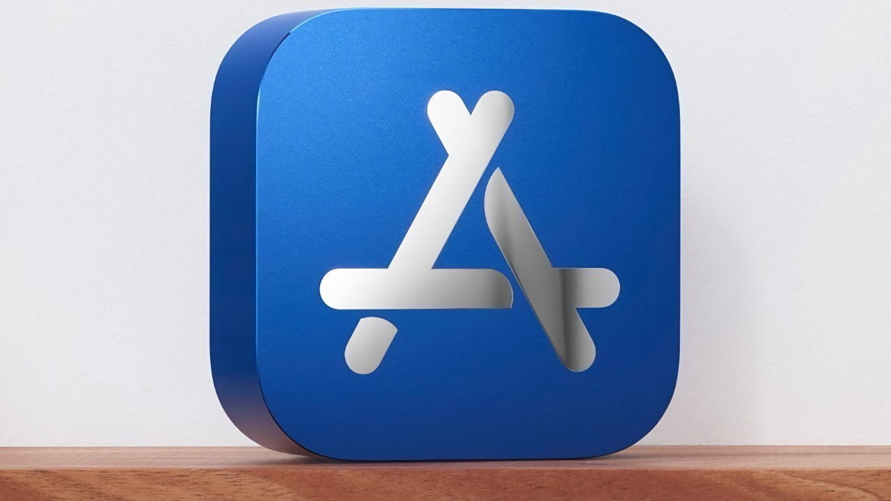 Blue cube with rounded edges featuring a white 3D overlapping sticks design resembling the App Store logo, placed on a wooden surface.