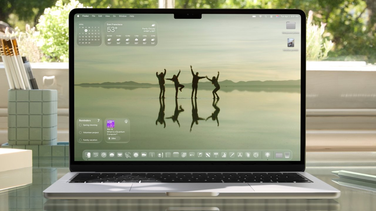 Laptop displaying a serene, reflective lake scene with four silhouetted people dancing under an overcast sky, surrounded by modern desktop interface and apps.