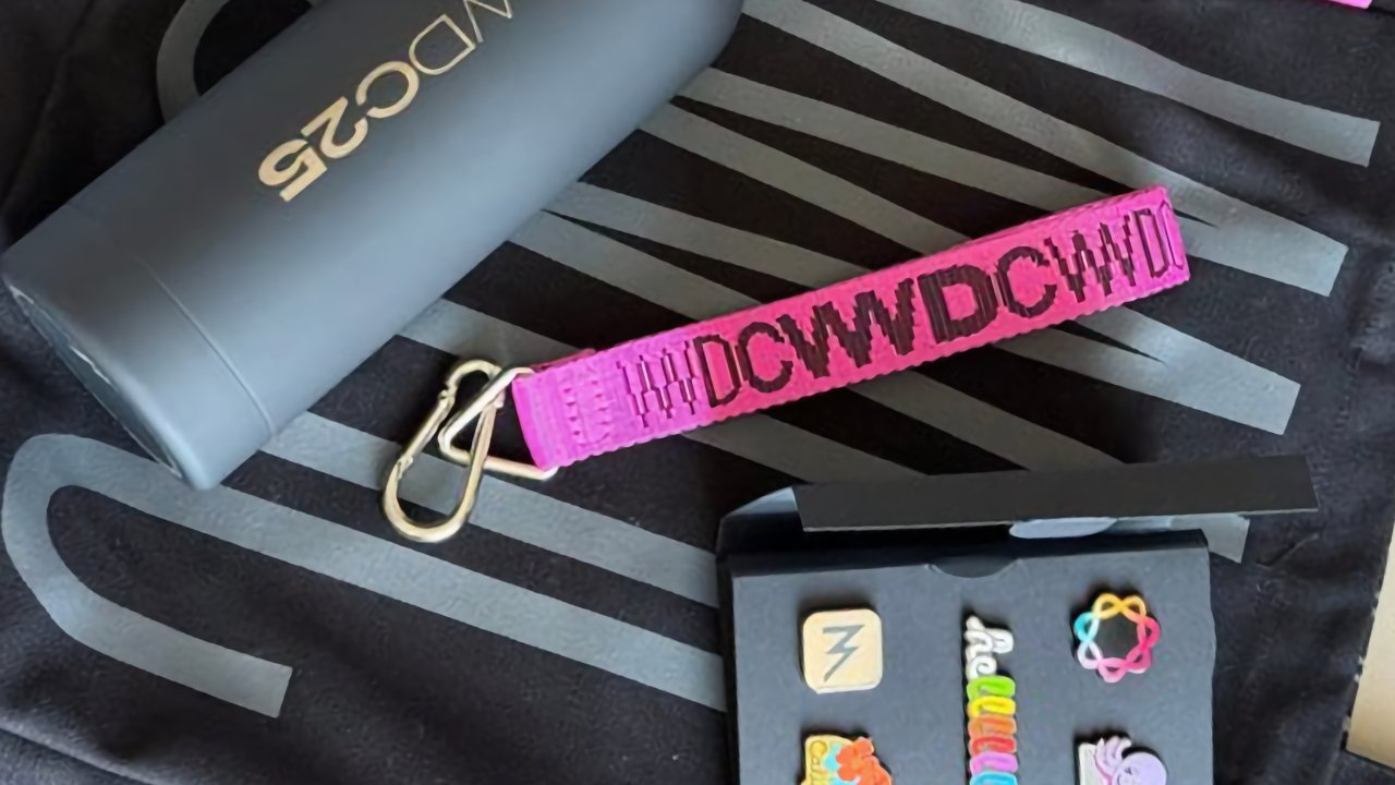 Black tumbler with gold lettering, pink keychain with text, black box with colorful pins depicting various symbols on a patterned background.