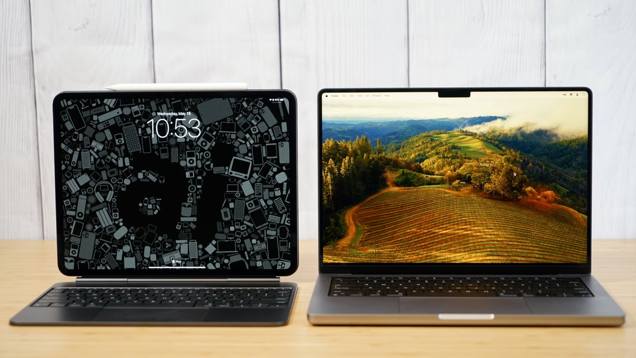 Two laptops on a wooden table, left screen displaying a digital clock with abstract design, right screen showing a scenic landscape with hills and trees.