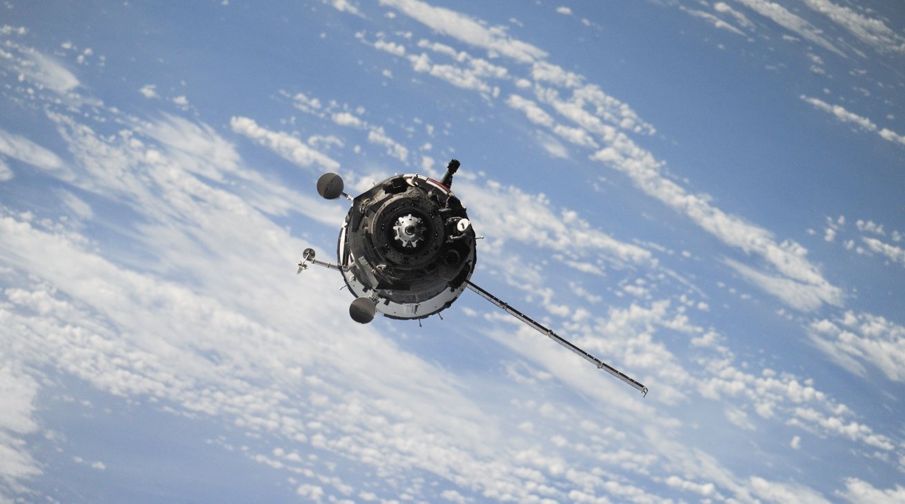 A satellite orbiting Earth, with a view of the planet's blue atmosphere and scattered clouds in the background.