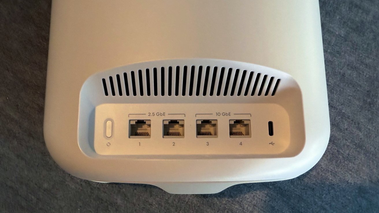 White electronic device with ventilation slits, four Ethernet ports labeled 2.5 GbE and 10 GbE, and one USB-C port against a dark surface.