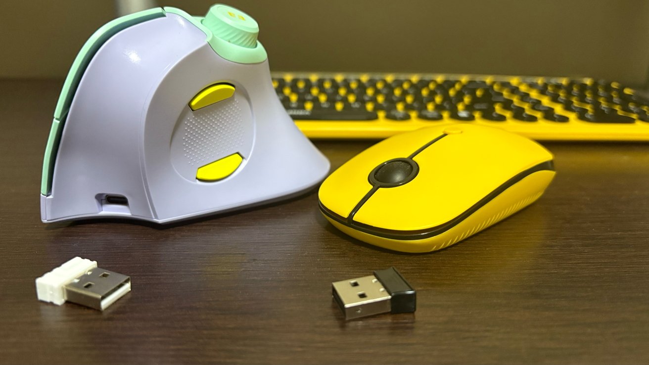 Yellow keyboard, vertical light gray mouse, yellow wireless mouse, and two USB adapters on a dark wooden surface.