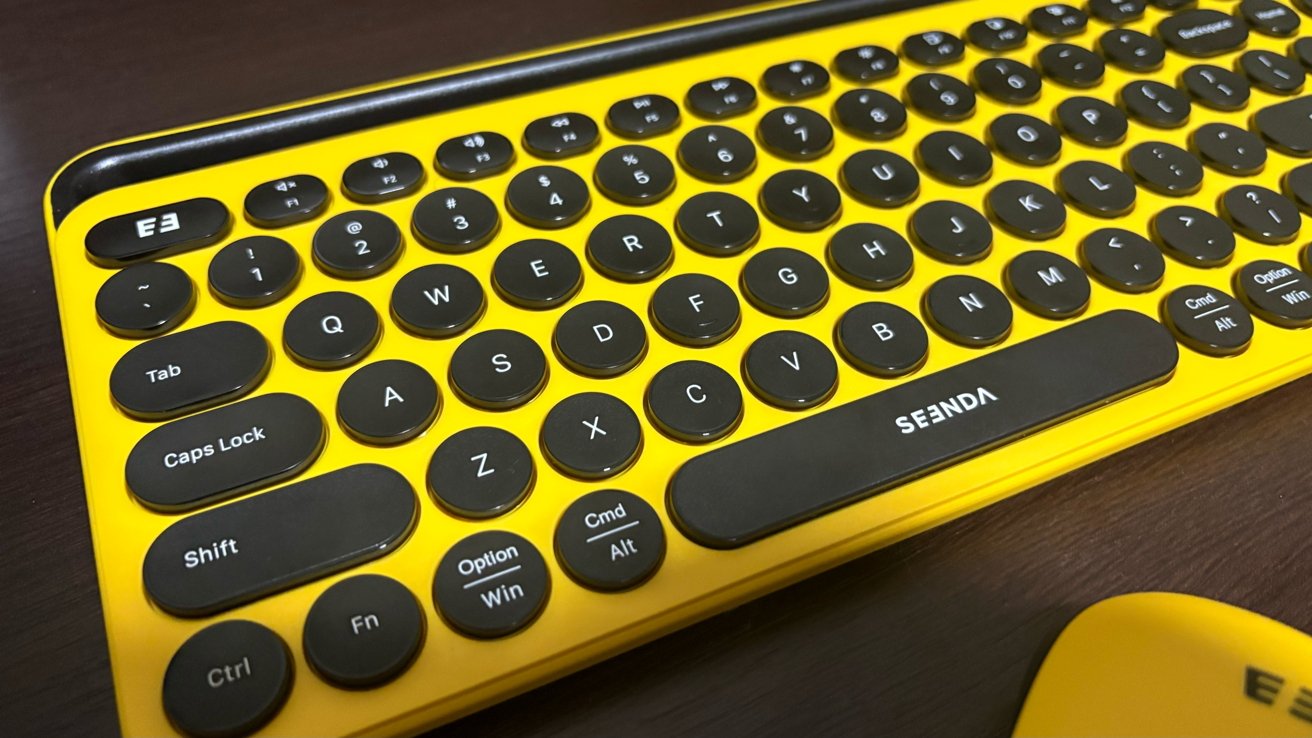 Yellow keyboard with round black keys, featuring white lettering. Includes function keys, special keys like Caps Lock, Shift, and media keys with a SEE-NDA label.