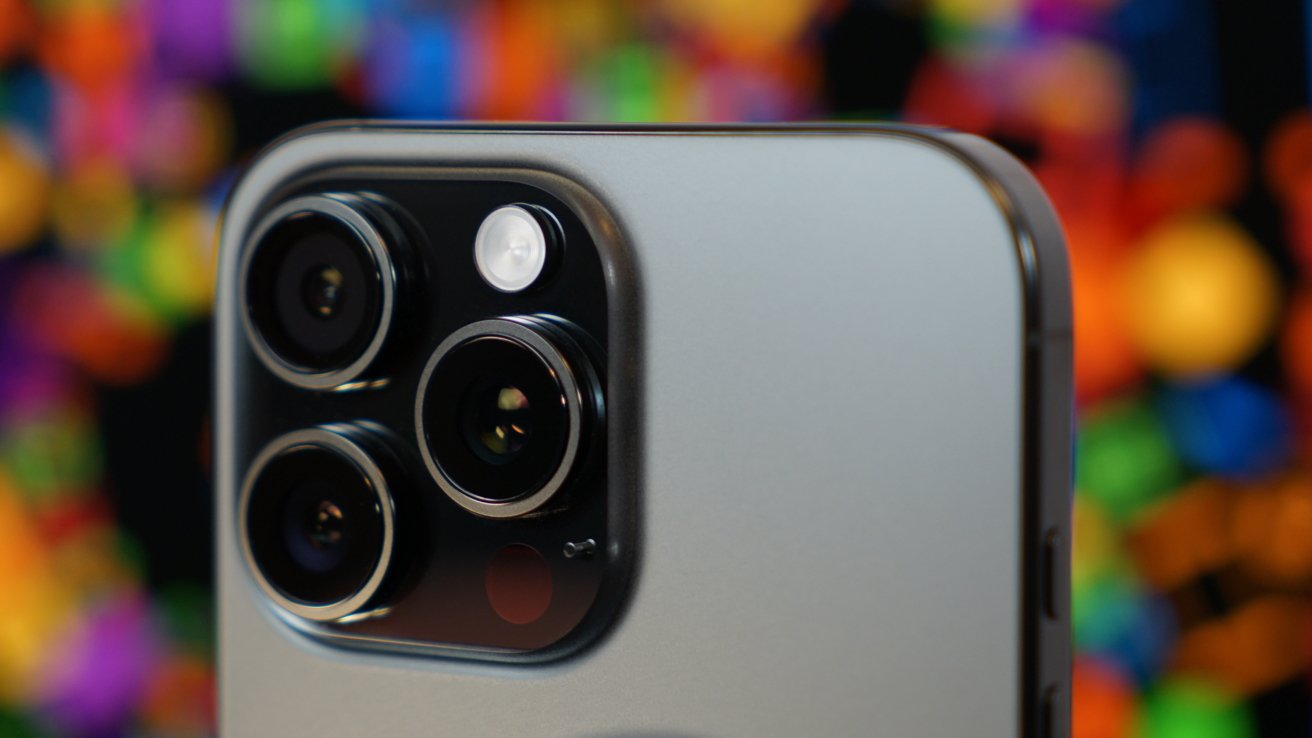 Close-up of a smartphone's triple-lens camera with colorful blurred lights in the background.