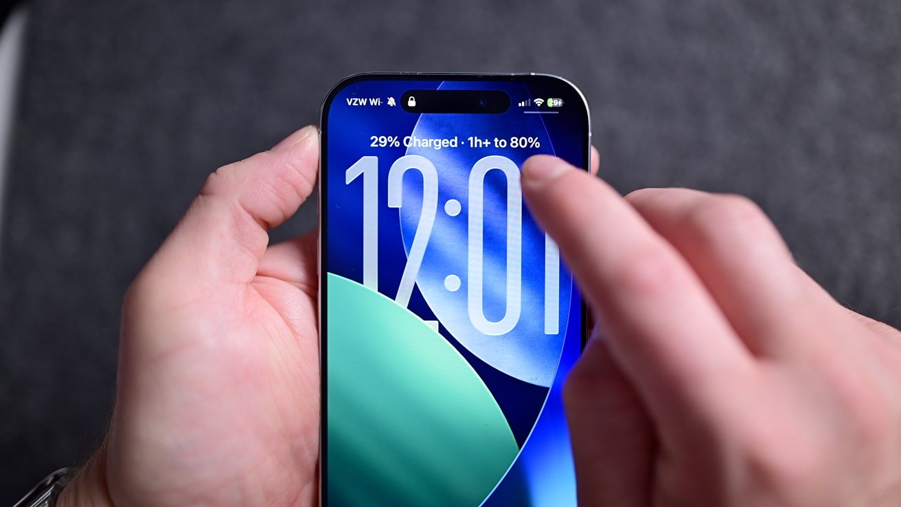 Hands holding a smartphone displaying a blue background screen showing 12:01, a battery icon at 29% charged, and time to reach 80%.