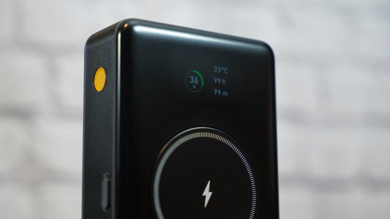 A rectangular electronic device with a circular charging symbol, digital display showing 36% battery, temperature 33C, and numbers 99h, 99m.