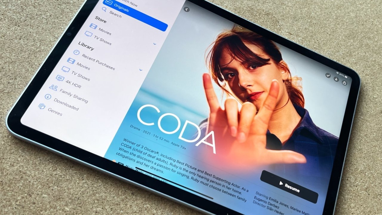 Tablet displaying movie library interface and 'CODA' movie poster with a woman signing in the foreground.