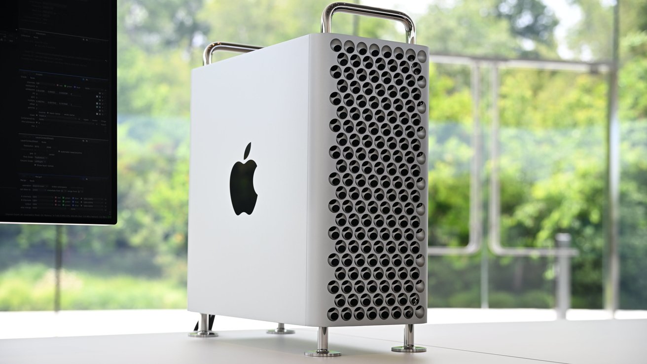 A sleek, metallic computer tower with a textured front panel featuring circular holes, resting on a desk beside a monitor.