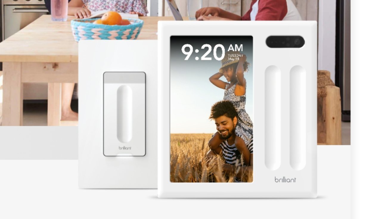 Smart home control panel showing time, date, and a photo of a smiling person carrying another in a wheat field, with people in the background at a table.