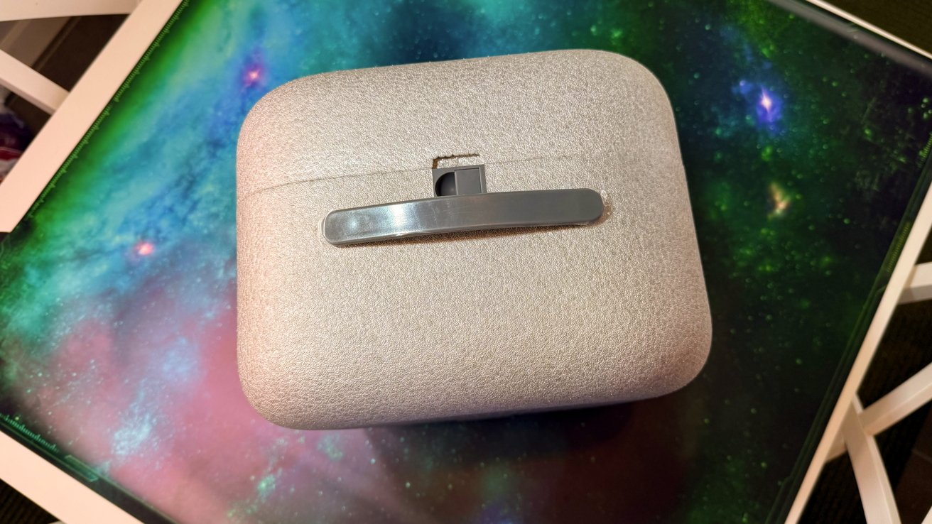 Beige textured suitcase with a metal handle, placed on a colorful galaxy-patterned surface.