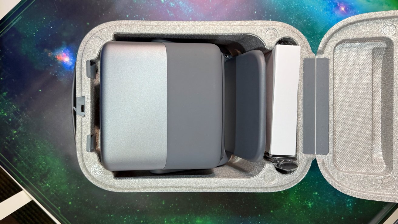 Gray drone nestled in a protective foam case on a colorful, space-themed background.