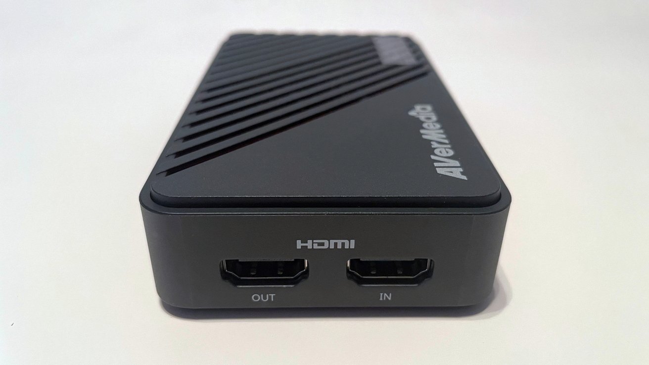 Black AVerMedia video capture device with HDMI input and output ports, diagonal ventilation slits on top, set against a white background.