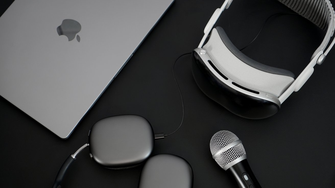 Laptop, futuristic headset, wireless headphones, and a microphone arranged on a dark surface.