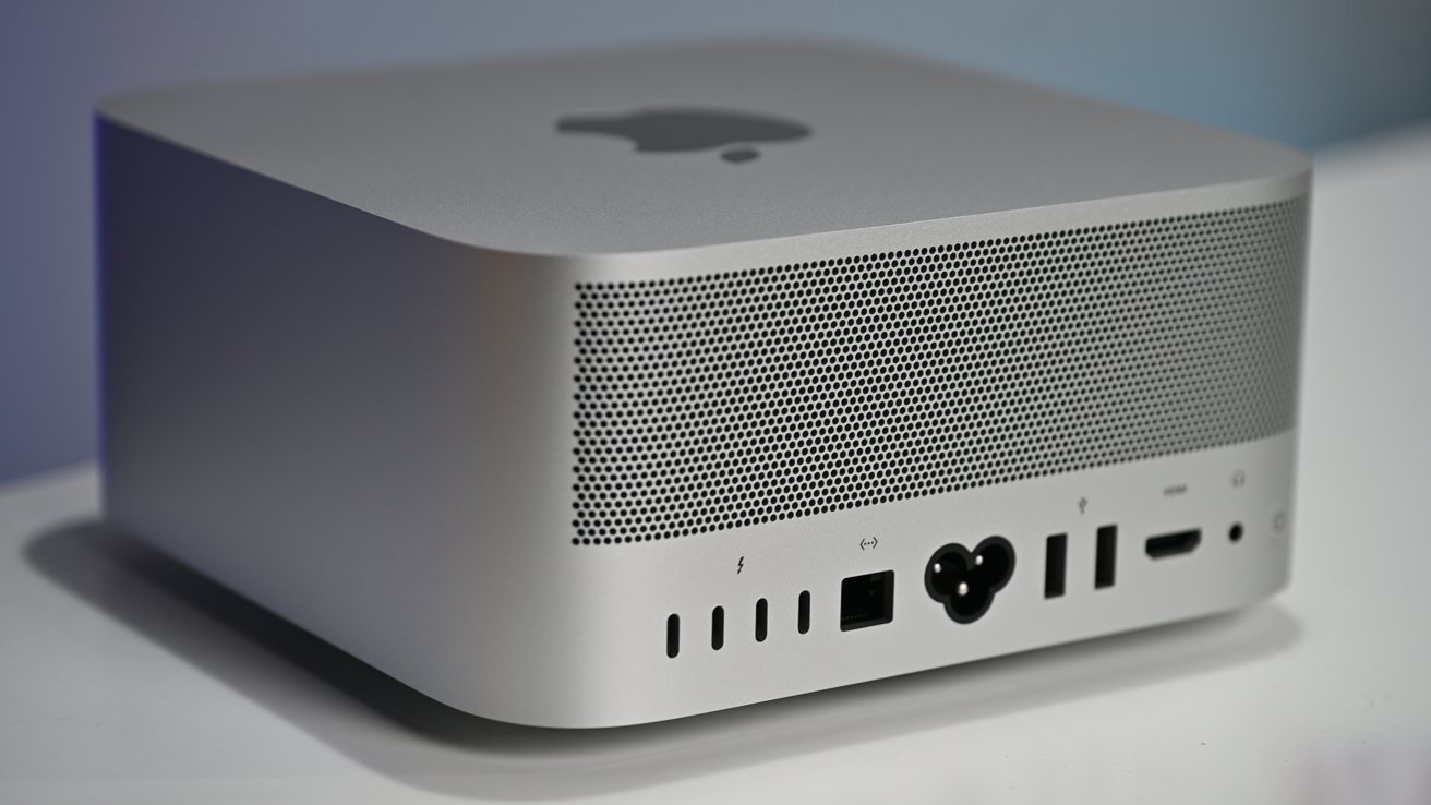 Square silver device with ventilation holes, Apple logo on top. Multiple ports on the back, including USB-C, HDMI, and power socket.
