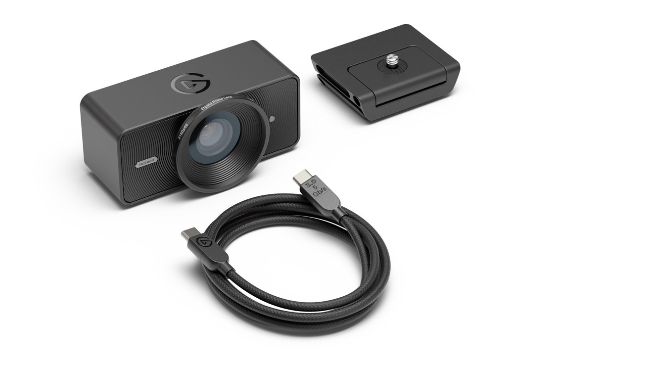 Black camera with lens, rectangular stand, and coiled USB cable on a white background.