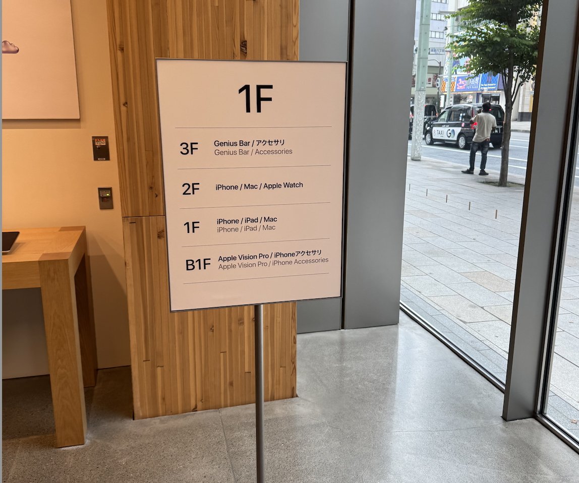 Indoor sign listing floor directories: 3F for Genius Bar and accessories, 2F for iPhone, Mac, Apple Watch, 1F for iPhone, iPad, Mac, B1F for Apple Vision Pro, iPhone accessories.