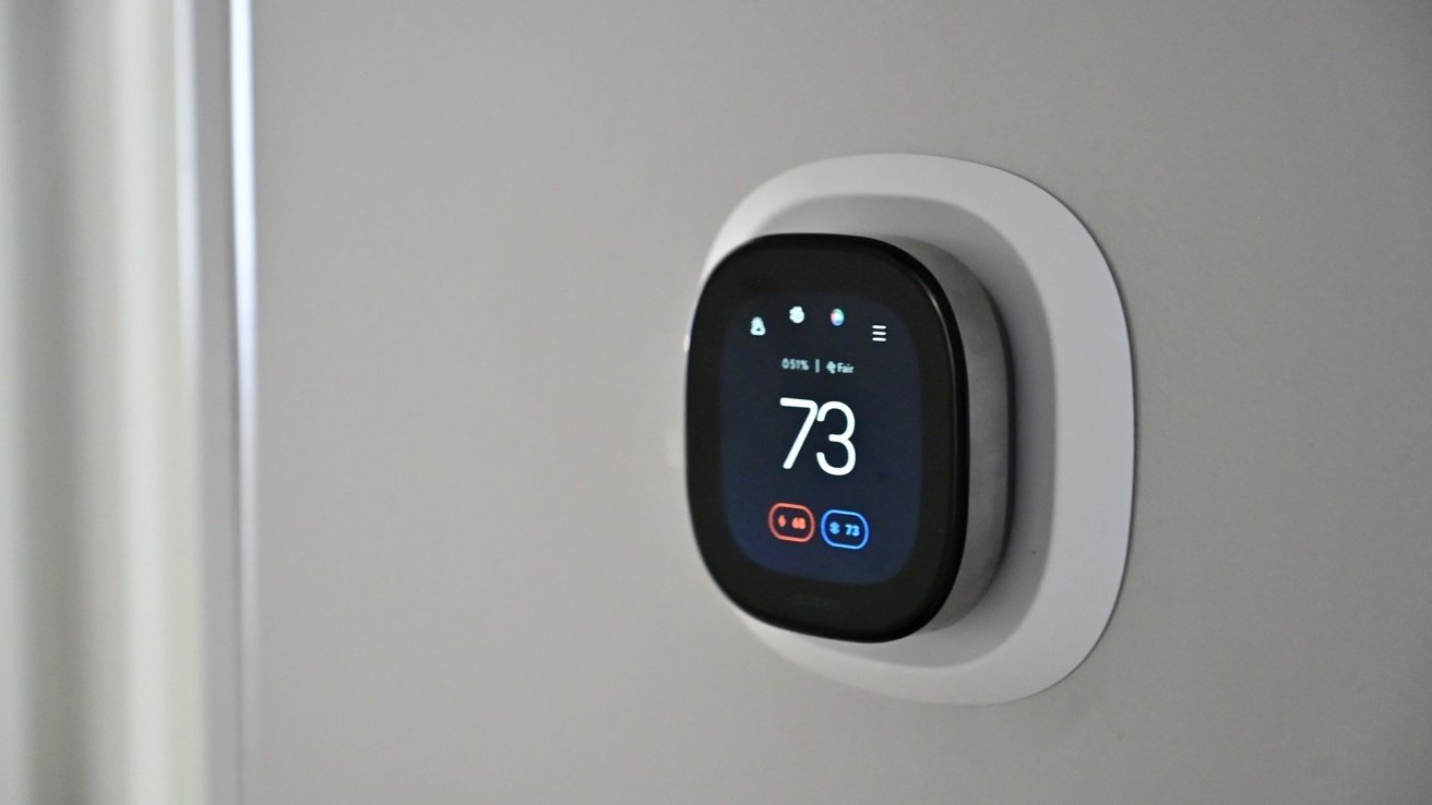 A smart thermostat installed on a white wall with a touchscreen