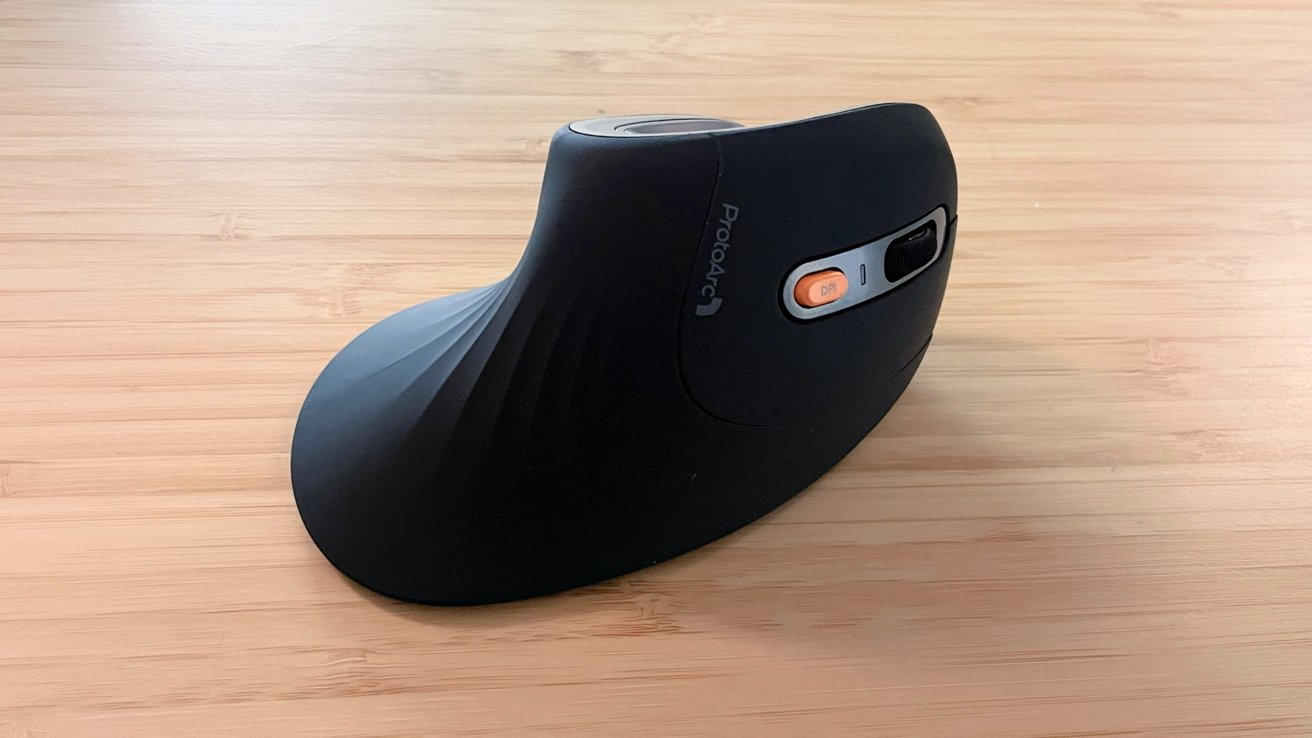 Ergonomic black vertical computer mouse on a light wood surface with an orange DPI switch visible.