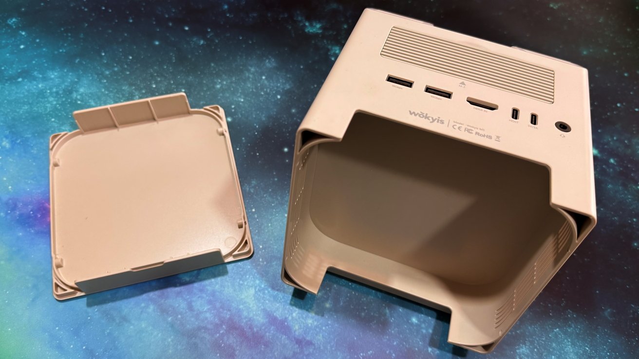 Beige computer case with open back panel showing ports including USB and HDMI on a blue and black cosmic background