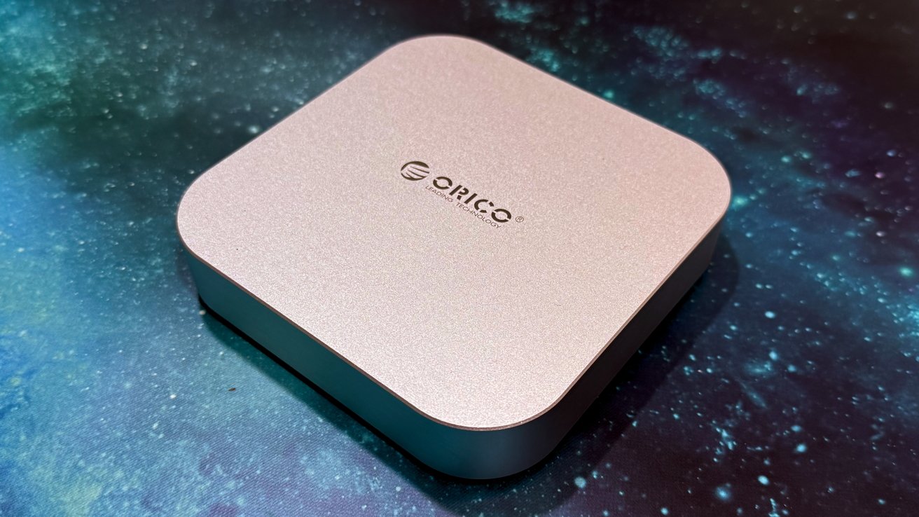 A sleek, square, metallic device with rounded corners on a starry, blue-toned surface; brand logo centered on top.