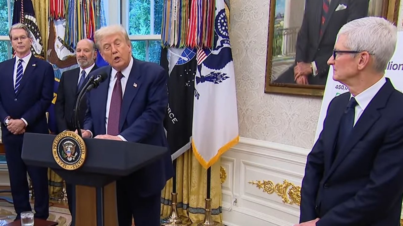 A group of men in suits stands in a room with flags, a podium, and a portrait in a formal setting.