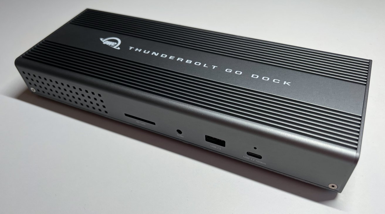 A rectangular dark gray docking station with grooves on top, labeled 'Thunderbolt Go Dock,' featuring various ports including USB, audio, and card reader slots on the front side.