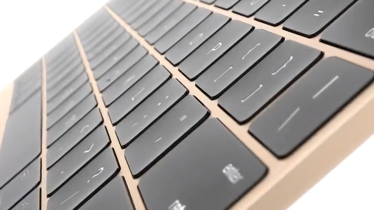 Close-up view of a thin, angled keyboard with black keys and white markings on a light-colored base.