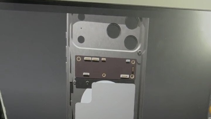 Interior view of a smartphone showing the camera module area with circular openings and connectors, partially disassembled.