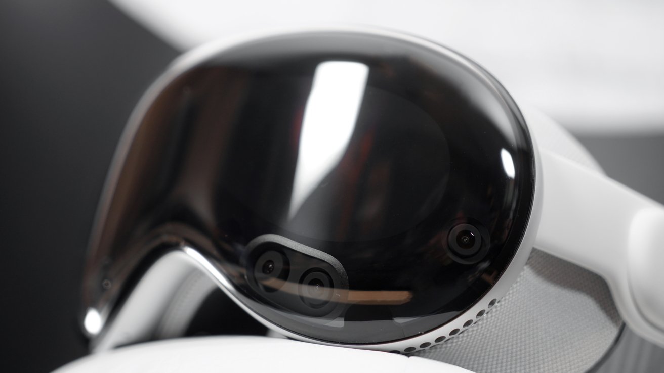 Futuristic headset with a sleek, dark reflective visor and integrated cameras, featuring a white and gray band, set against a blurred background.